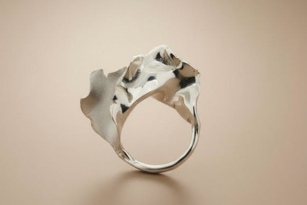 Silver ring with a textured design on a gray background