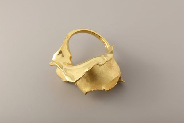 Gold ring with a unique design on a gray background