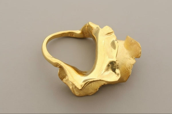 Gold ring with a unique design on a gray background