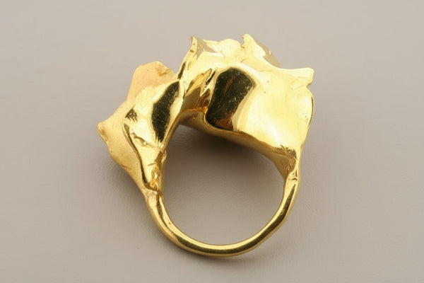 Gold ring with a unique design on a gray background