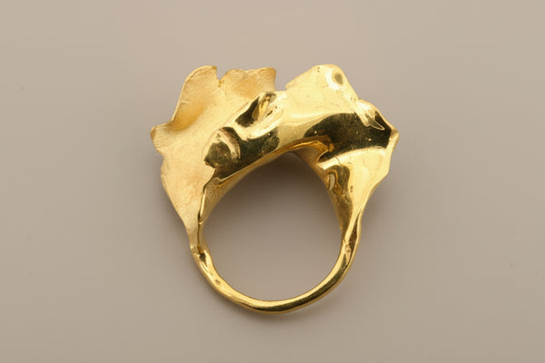 Gold ring with a unique design on a gray background