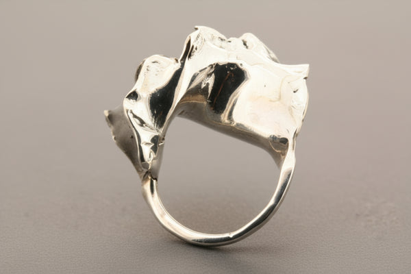 Silver ring with a textured design on a gray background