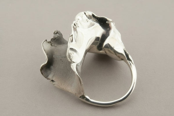 Silver ring with a unique, organic design on a gray background