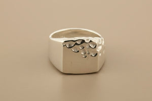Silver ring with a textured surface on a gray background