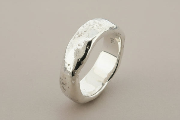 Silver ring with a textured surface on a gray background