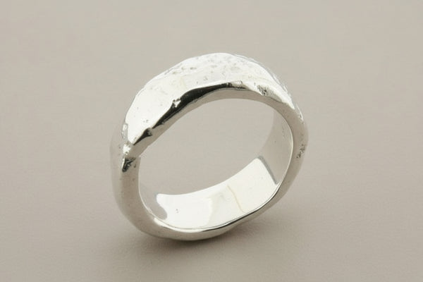Silver ring with a textured surface on a gray background
