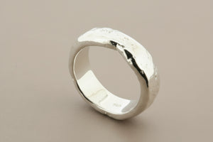 Silver ring with a textured surface on a gray background