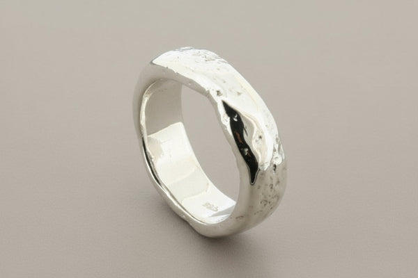 Silver ring with a textured surface on a gray background