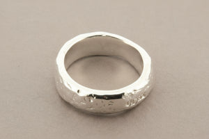 Silver ring with a textured surface on a gray background