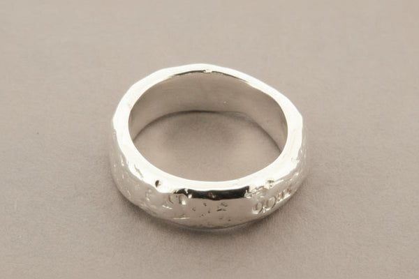Silver ring with a textured surface on a gray background