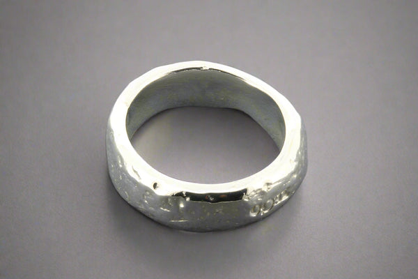 Silver ring with a textured surface on a gray background