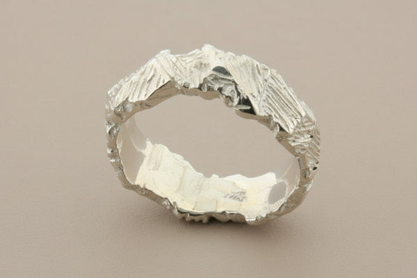 Silver ring with a textured surface on a dark gray background