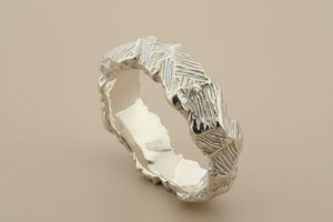 Silver ring with textured design on a dark gray background
