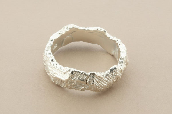 Silver ring with textured surface on a gray background