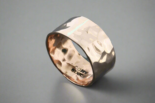 Copper ring with a textured band on a dark grey background