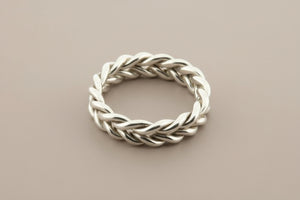 Silver braided ring on a gray background