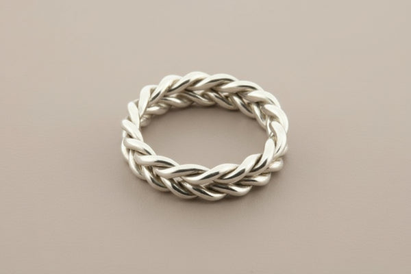 Silver braided ring on a gray background