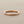Load image into Gallery viewer, A minimalist, polished rose gold band ring resting on a dark gray textured surface.

