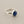 Load image into Gallery viewer, A sterling silver ring featuring a round, bezel-set dark blue gemstone, photographed on a dark gray textured surface.
