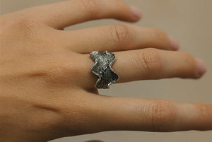 Silver ring on a finger against a neutral background