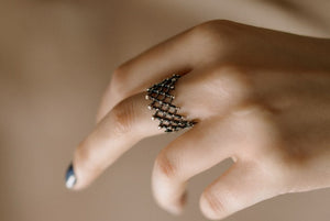 Close-up of a hand wearing a decorative ring on a blurred background