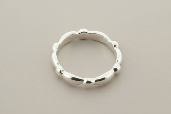 Silver ring with a textured design on a gray background