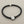 Load image into Gallery viewer, Black bracelet with a textured silver charm on a gray background
