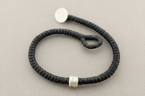 Black bracelet with silver ends on a gray background