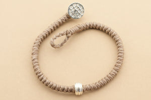 Gray beaded bracelet with silver beads on a gray background