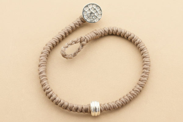Gray beaded bracelet with silver beads on a gray background