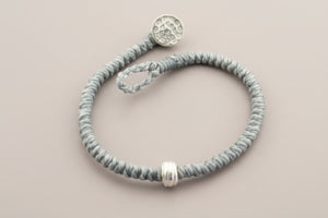 Gray beaded bracelet with silver beads on a gray background