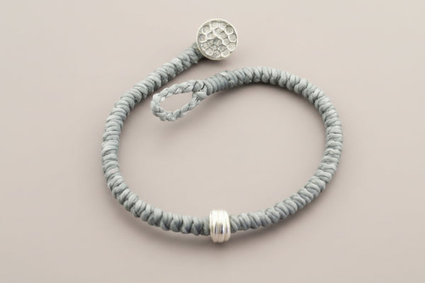 Gray beaded bracelet with silver beads on a gray background