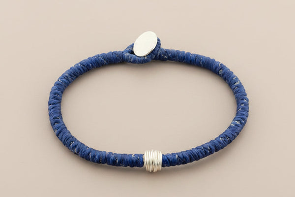 Blue beaded bracelet with a silver clasp on a gray background
