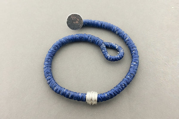 Blue textured bracelet with silver accents on a gray background