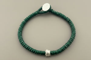 Green bracelet with silver accents on a gray background