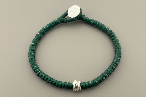 Green bracelet with silver accents on a gray background