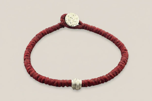 Red bracelet with silver clasp on a gray background