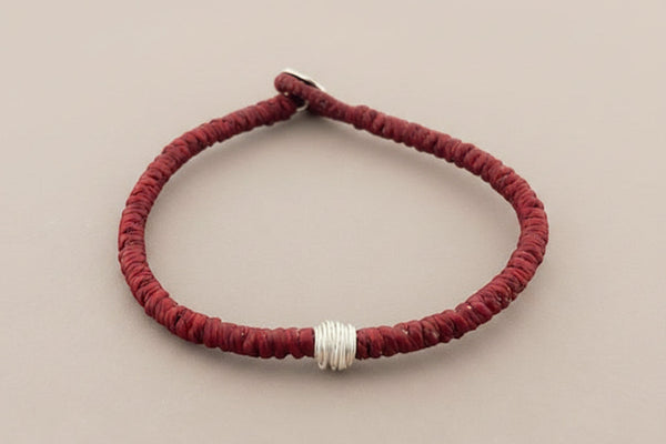 Red braided bracelet with a silver clasp on a gray background