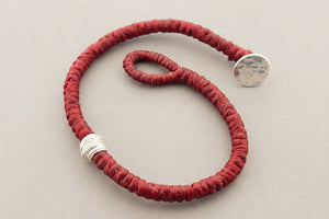 Red bracelet with silver accents on a gray background