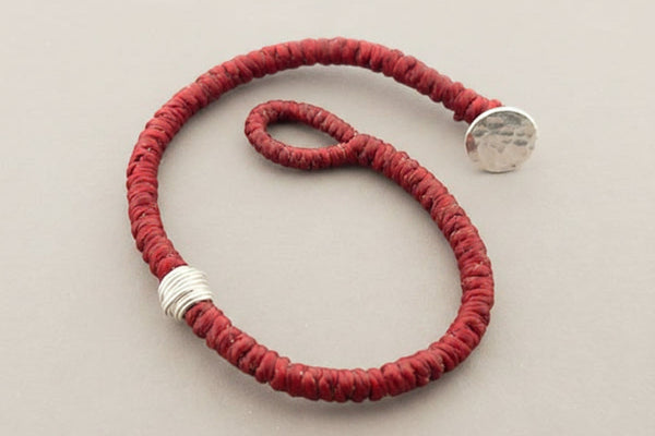 Red bracelet with silver accents on a gray background