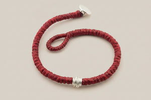 Red bracelet with silver accents on a gray background
