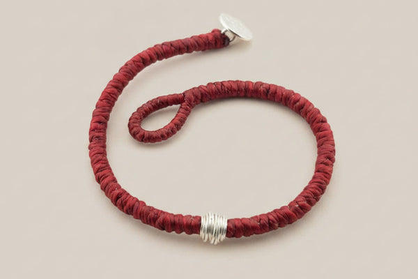 Red bracelet with silver accents on a gray background