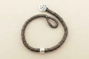 Textured bracelet with silver accents on a gray background