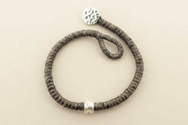 Textured bracelet with silver accents on a gray background