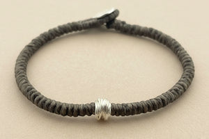 Bracelet with textured brown band and silver accents on a gray background