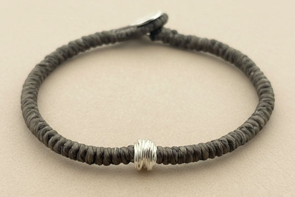 Bracelet with textured brown band and silver accents on a gray background