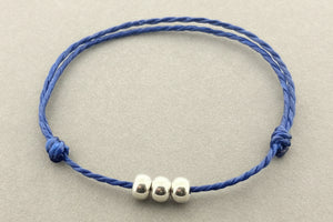 Blue bracelet with silver beads on a gray background
