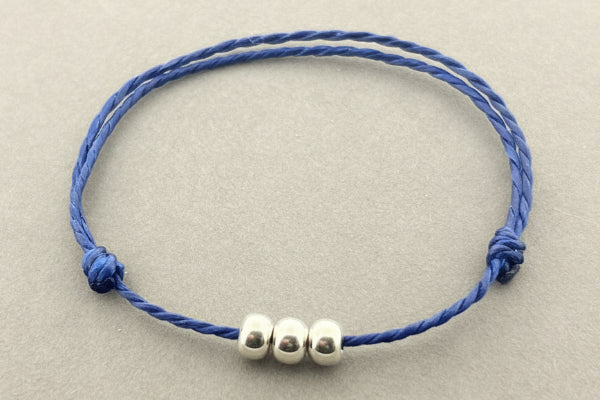 Blue bracelet with silver beads on a gray background