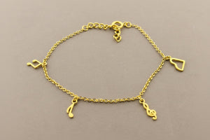 Gold bracelet with musical note charms on a gray background