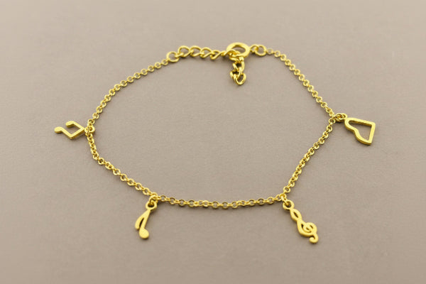 Gold bracelet with musical note charms on a gray background
